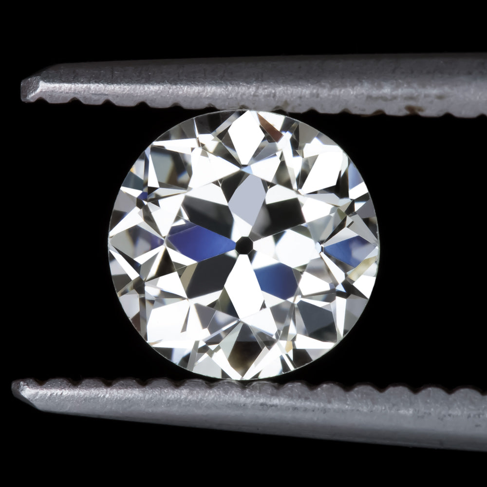 0.75ct old European cut loose diamond with H color and VS2 clarity held in tweezers on a dark background.