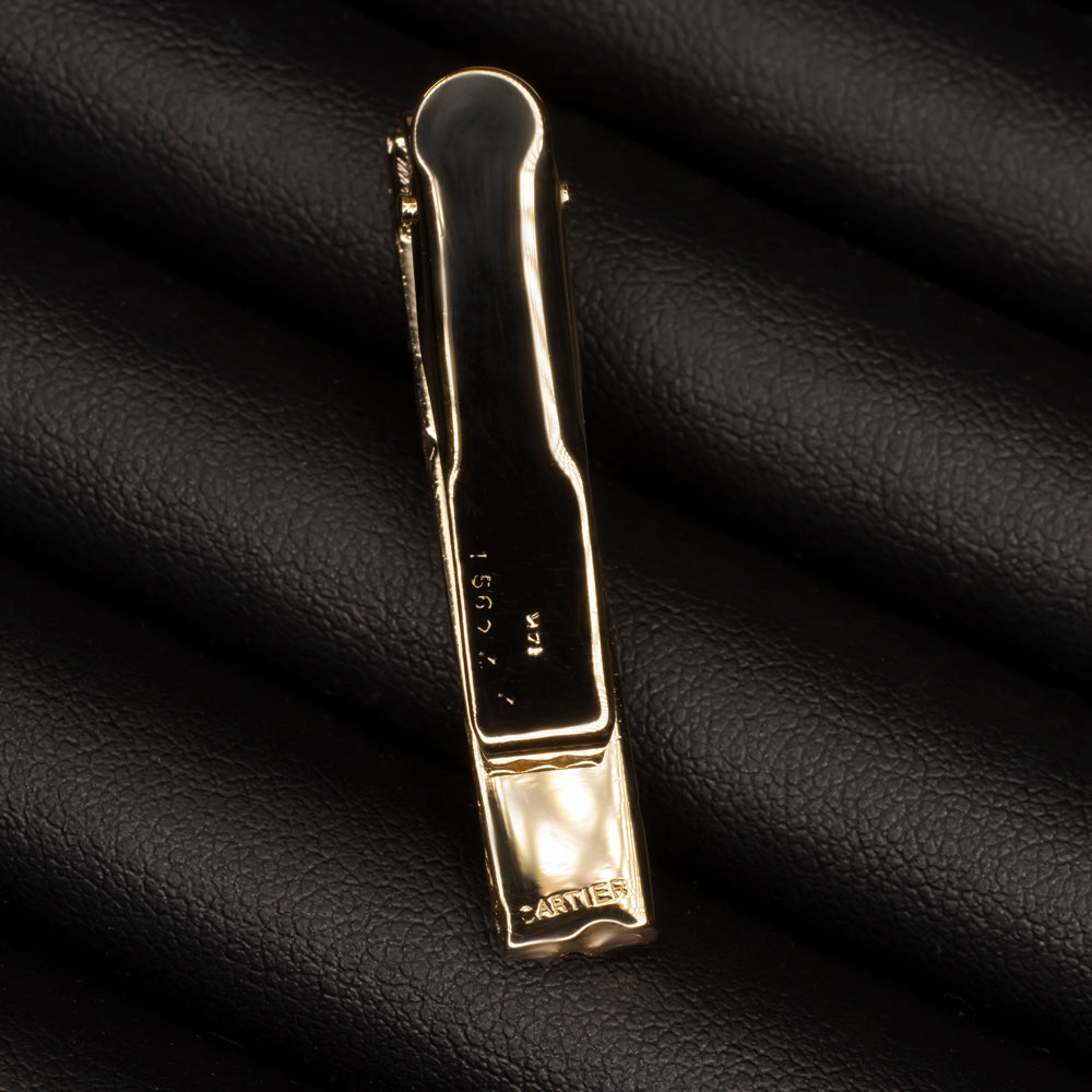 Vintage Cartier 14k gold tie bar with hallmark, featuring sleek design and textured finish on black leather background.