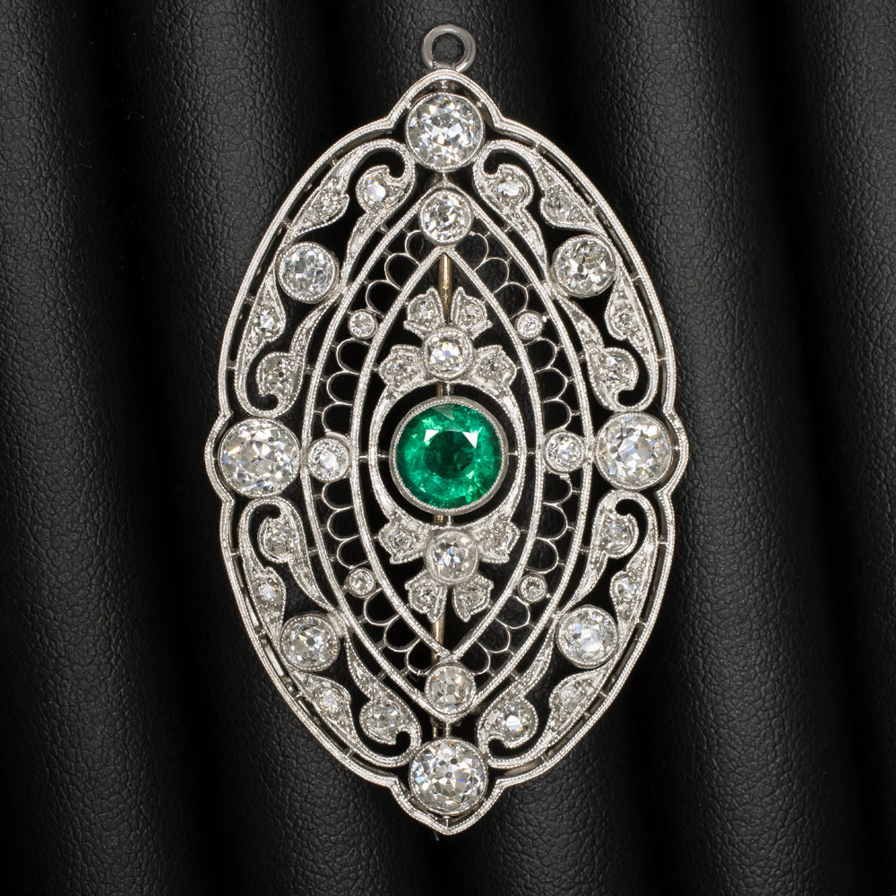 Art Deco vintage pin pendant featuring a green emerald and old cut diamonds in intricate platinum filigree design.