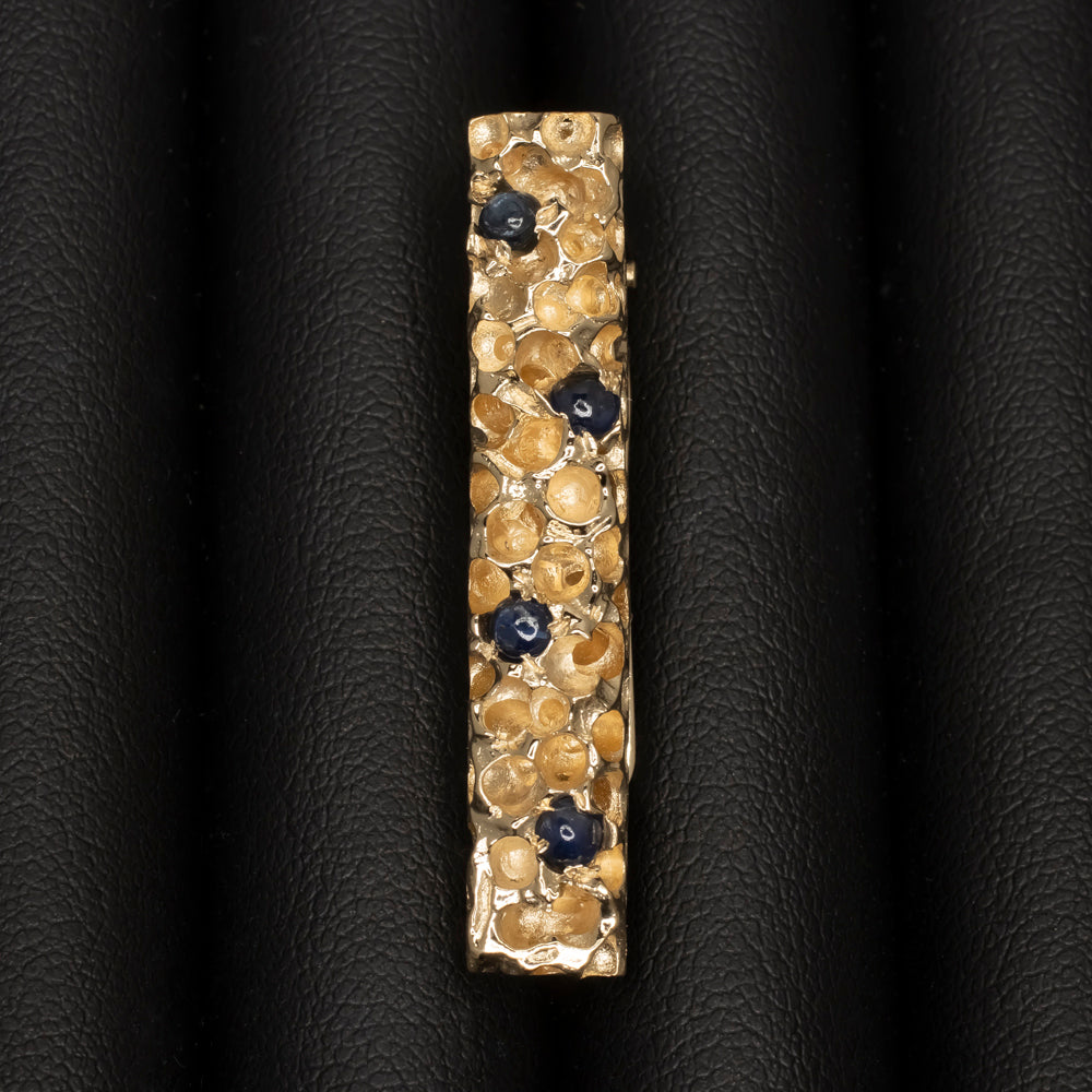 Vintage Cartier tie bar in 14k yellow gold with sapphire cabochons, textured gold nugget design, 1970s elegance.