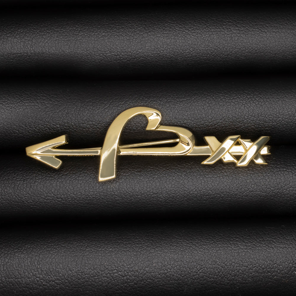 Vintage Tiffany and Co 18k yellow gold Paloma Picasso heart and arrow pin brooch on black background.